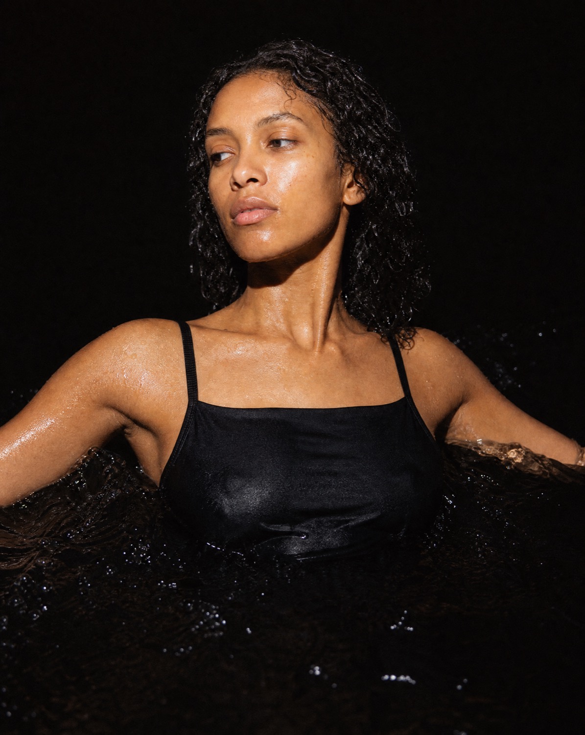 The black UNI x GLOW camisole, shot close in low light